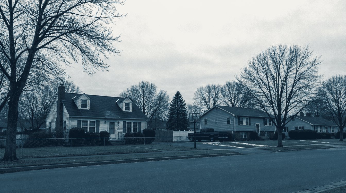 A residential street of cape-cod and split-level houses on a bare-tree winter morning